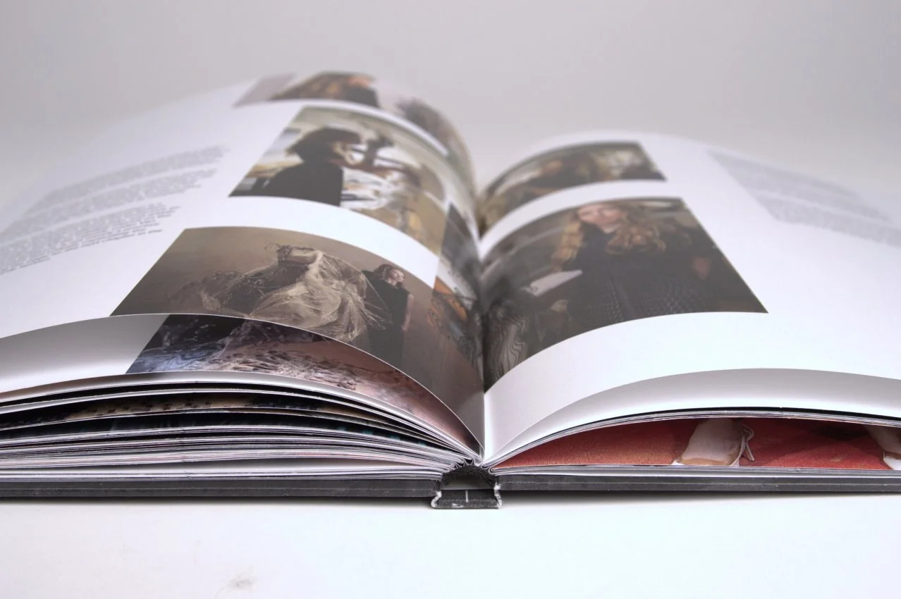 The book photographed from below at an angle, showing multiple spreads, page curl, and the binding