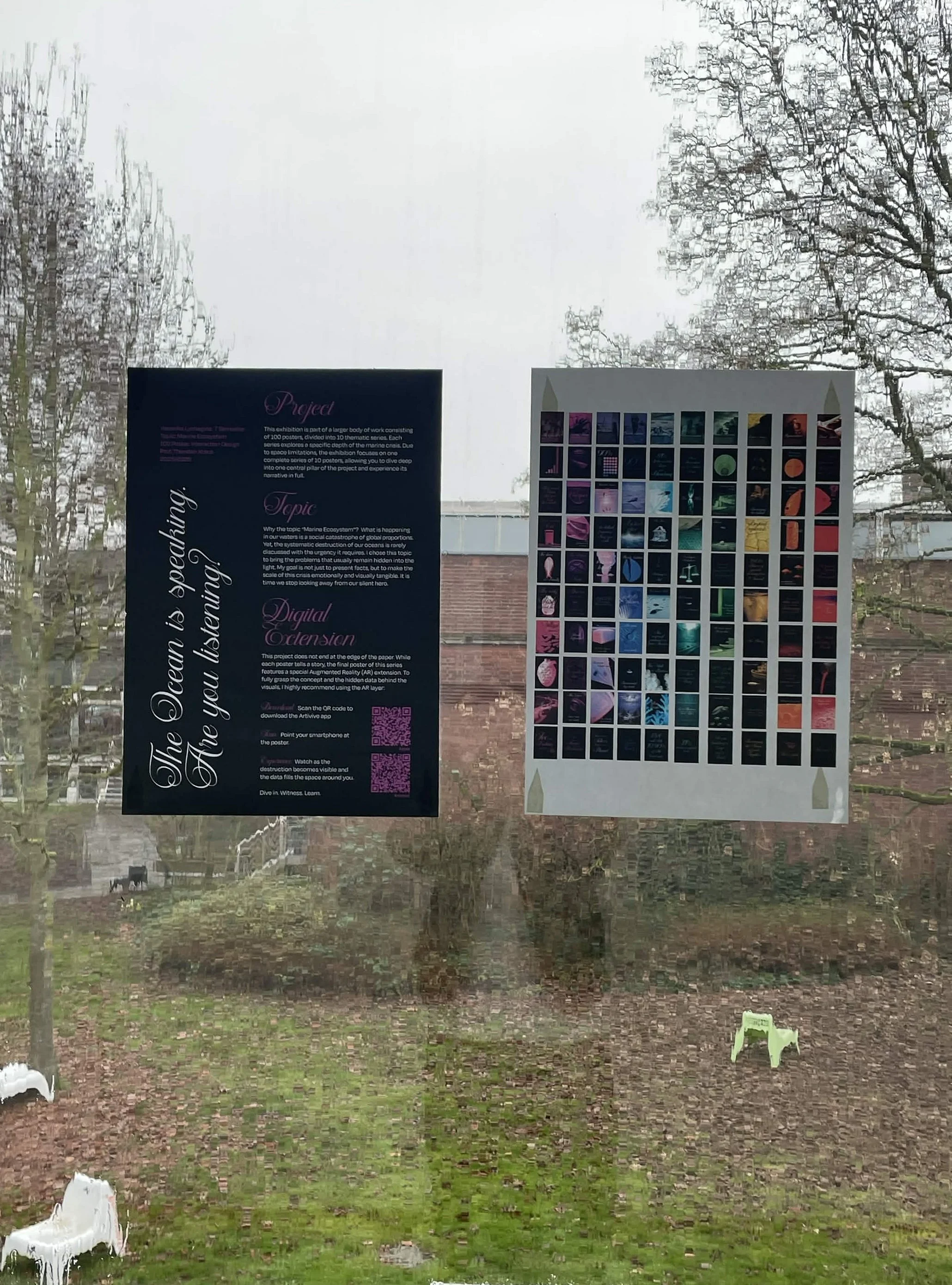 Window installation at the Werkschau: posters mounted on glass with campus grounds visible behind